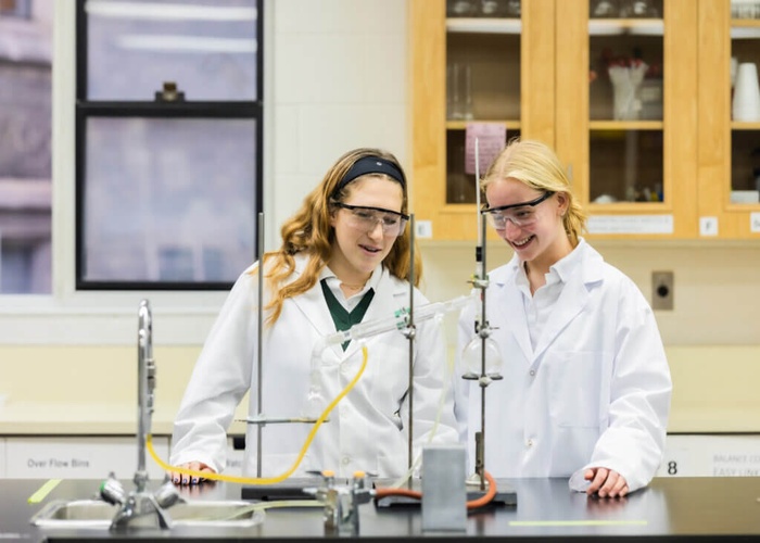 실험실에서 실험복과 고글을 착용한 학생들2명