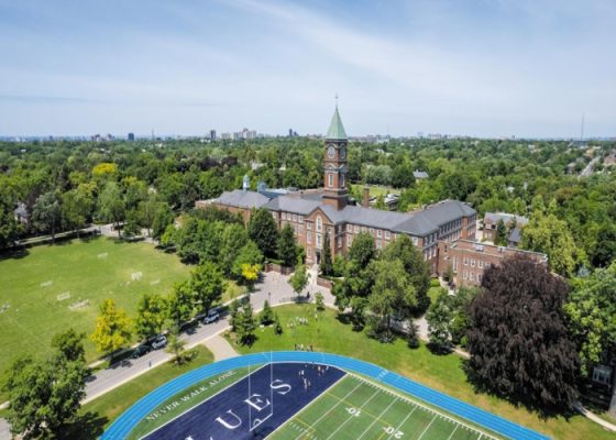 1 UCC College 전경, 맑은 하늘과 푸른 잔디, 숲 사이 건물